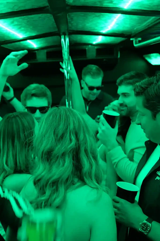 Guests dancing inside the party bus under green LED lighting
