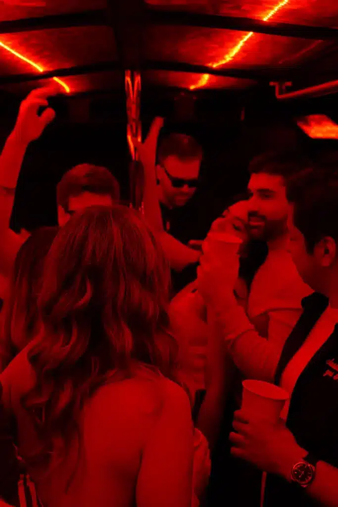 Friends partying inside a Luxus party bus with red LED lights