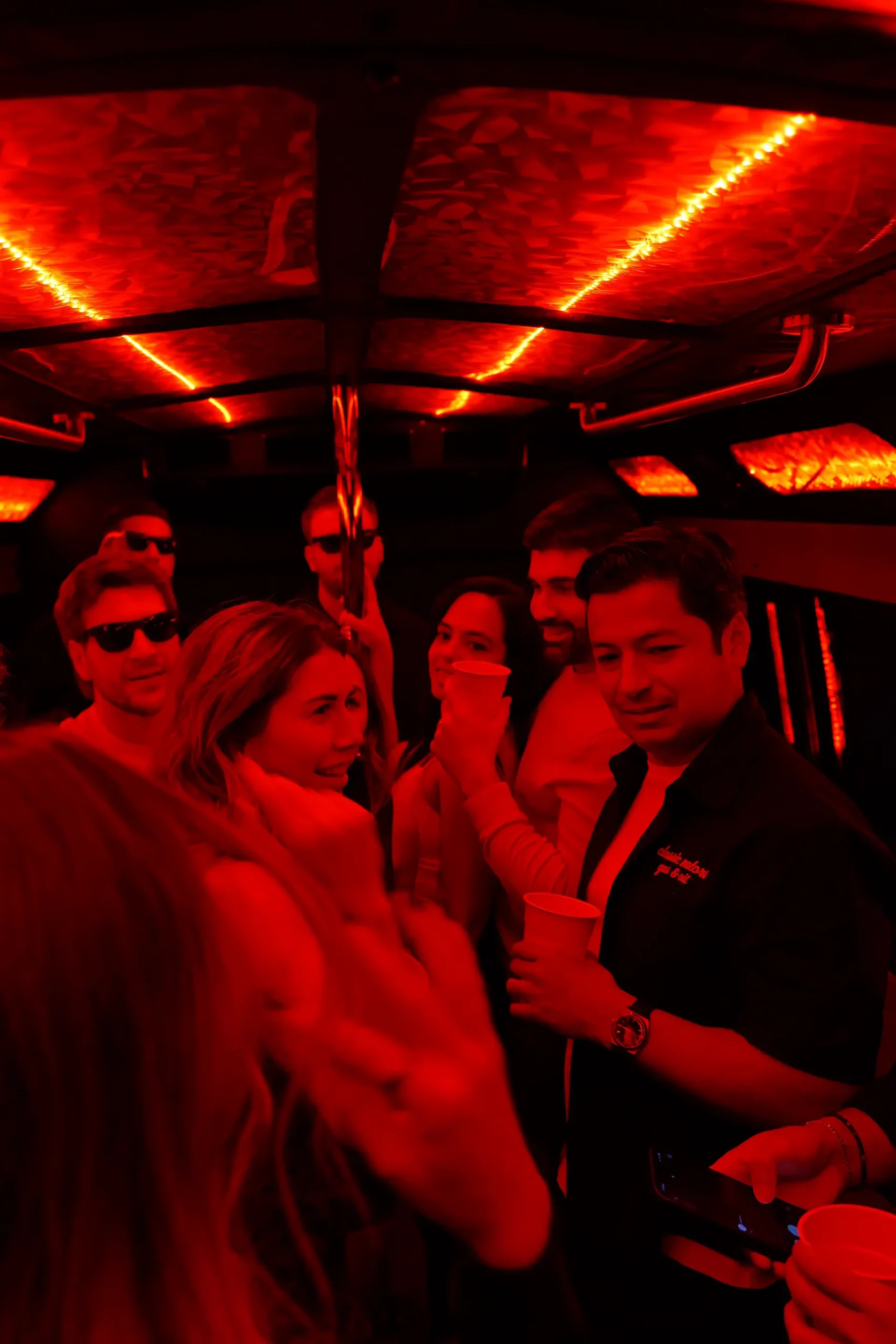 Group of friends posing inside a party bus with red LED lighting