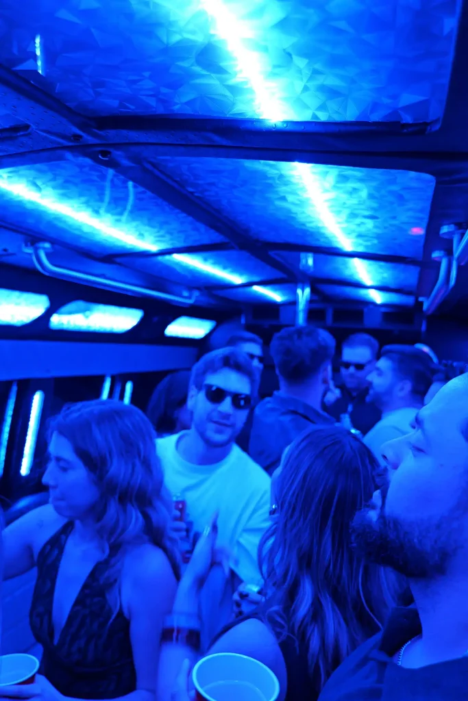 Friends smiling inside a party bus with blue LED lighting