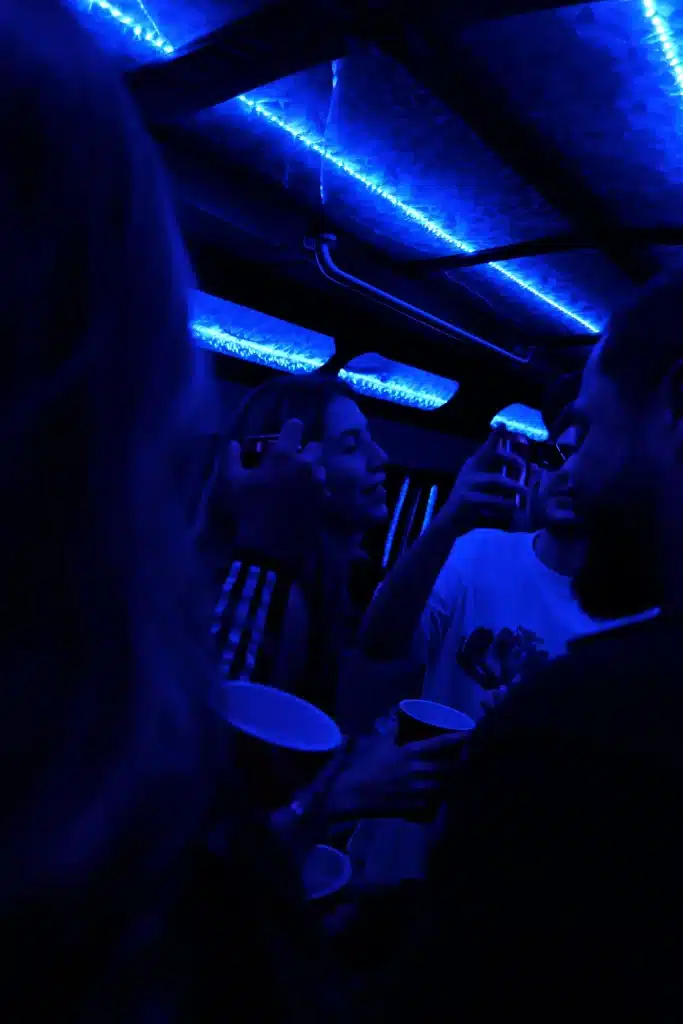 Party bus interior with blue LED lights and guests holding cups