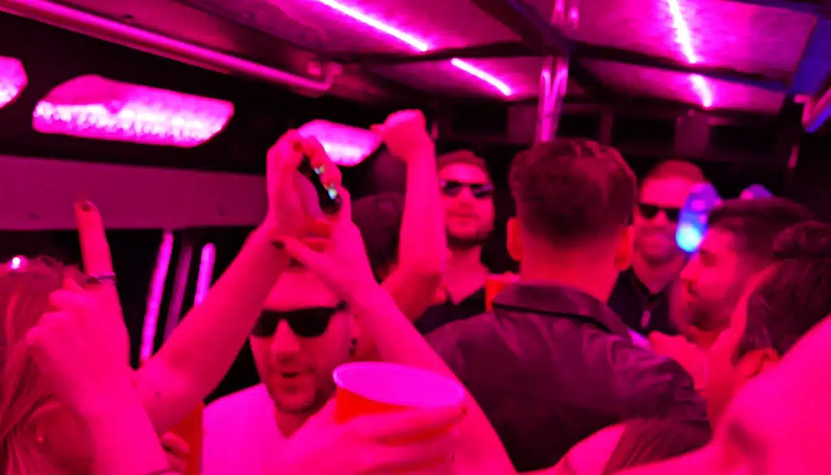 Party bus guests enjoying a night out under pink and purple LED lights
