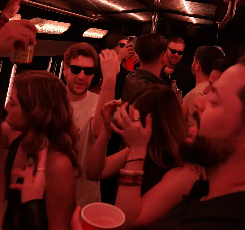 Guests dancing and celebrating inside a Luxus party bus in Houston under red LED lights