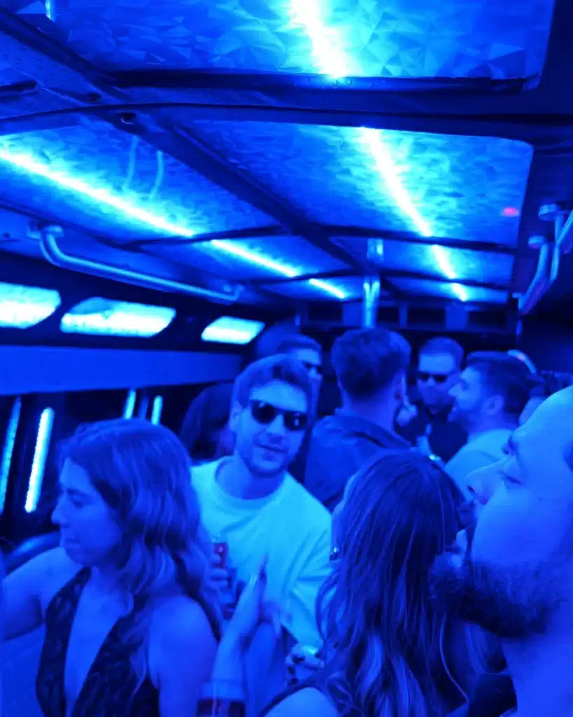 Friends smiling inside a party bus with blue LED lighting