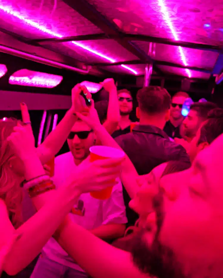 Party bus guests enjoying a night out under pink and purple LED lights
