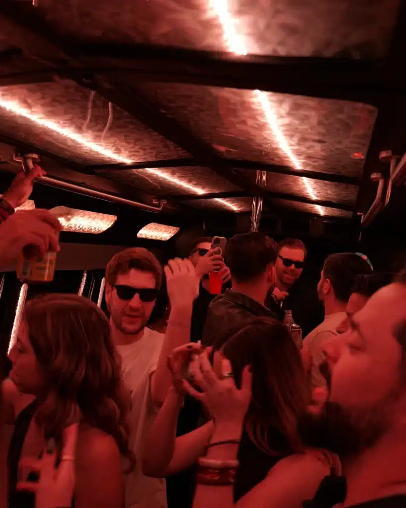 Group of friends with sunglasses inside a Luxus party bus with warm LED lights