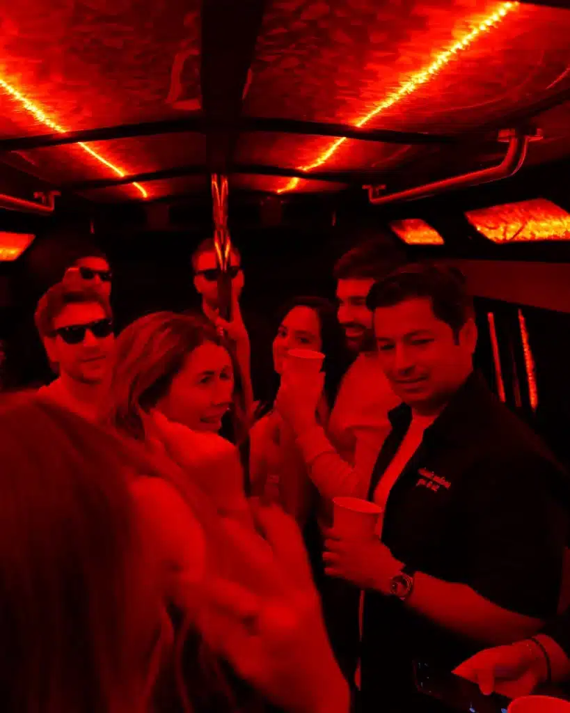 Group of friends posing inside a party bus with red LED lighting
