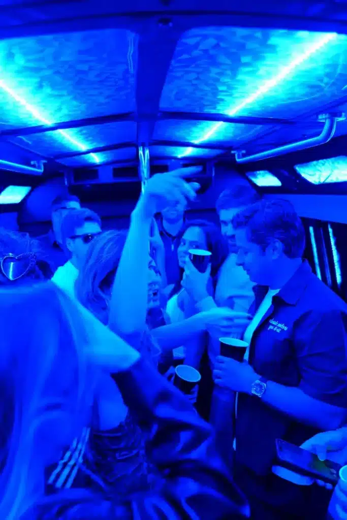 Group celebrating inside the party bus under blue LED lighting