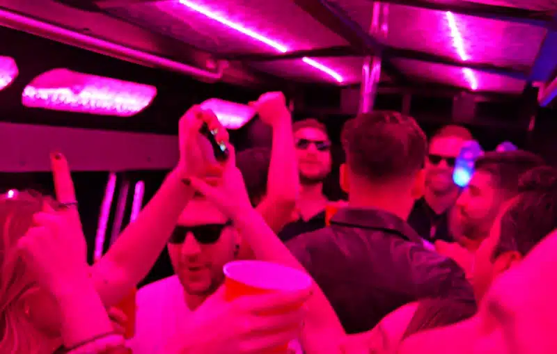 Party bus guests enjoying a night out under pink and purple LED lights