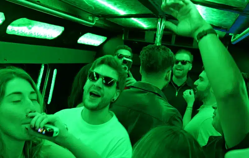 Friends partying inside a Luxus party bus with green LED lights