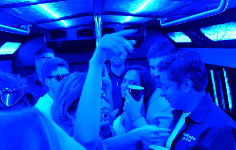 Guests celebrating inside a Luxus party bus with blue LED lights